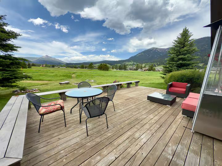 The back deck: outdoor seating and a stone-topped table with an unobstructed view of Lone Peak across the meadow below.